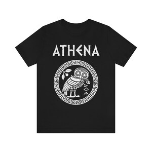 May include: Black t-shirt with a white graphic of the Greek goddess Athena's owl with the word "ATHENA" above it.