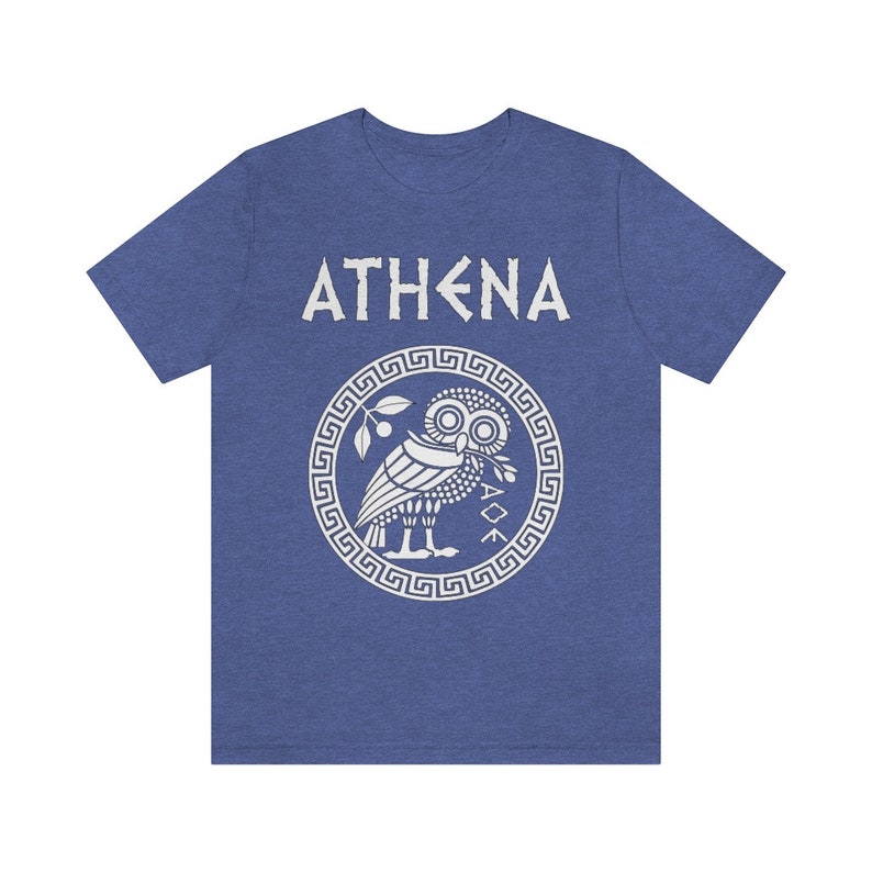 May include: A blue t-shirt with a white graphic of the Greek goddess Athena. The graphic features an owl with an olive branch in its beak, surrounded by a circular design with a Greek key pattern. The text "ATHENA" is printed above the graphic.