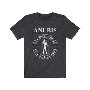 Op de afbeelding: Een donker grijs gem&ecirc;leerd t-shirt met een witte afbeelding van Anubis, de Egyptische god van de dood. De afbeelding bevat de tekst "Anubis, God van de Doden, Heer van de Duat".