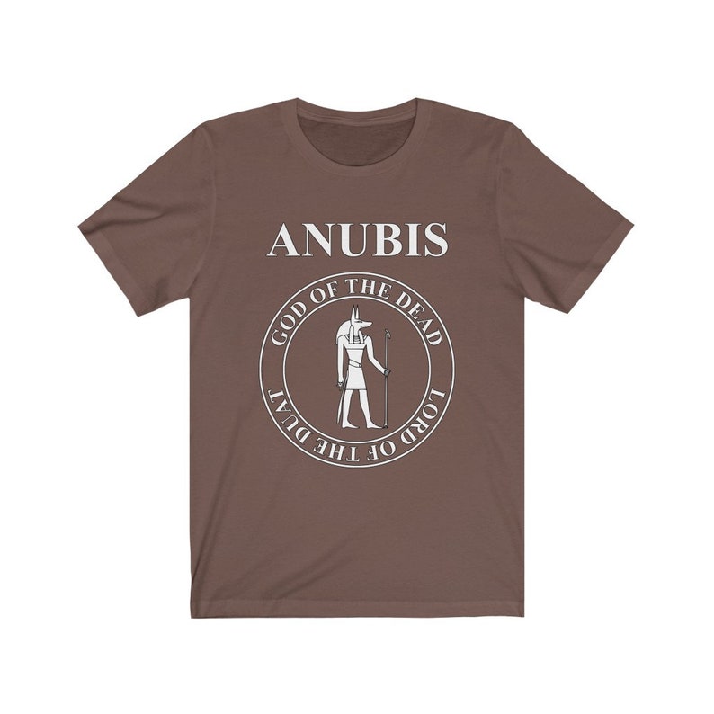 Op de afbeelding: Een bruin t-shirt met een witte afbeelding van Anubis, de Egyptische god van de dood. De afbeelding bevat de tekst "Anubis, God van de Doden, Heer van de Duat".