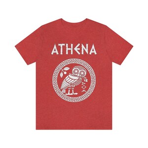 May include: Red t-shirt with a white graphic of the Greek goddess Athena's owl and the word "ATHENA" in white.