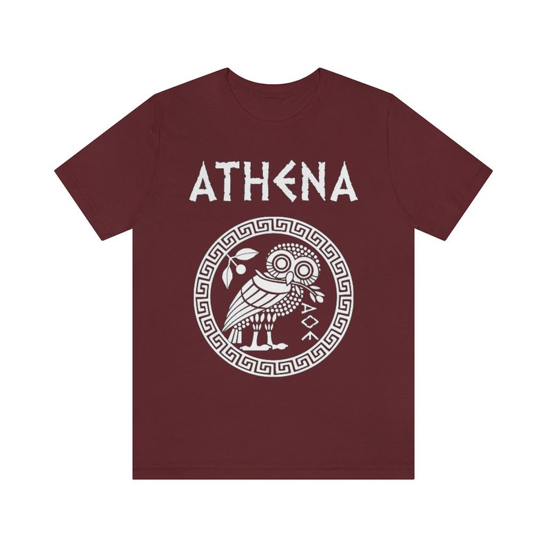 May include: A maroon t-shirt with a white graphic of the Greek goddess Athena's owl with the text "ATHENA" above it.