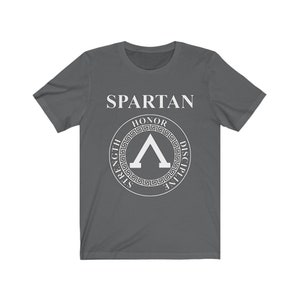 May include: A dark gray t-shirt with a white Spartan logo. The logo features a shield with the words "Honor, Strength, Discipline" surrounding it.