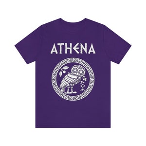 May include: Purple t-shirt with a white graphic of an owl inside a circle with a Greek key border. The text "ATHENA" is above the owl.