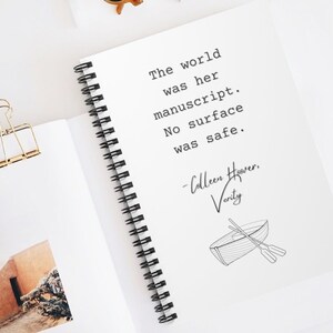 May include: A white notebook with a black spiral binding. The notebook has a quote from the book "Verity" by Colleen Hoover: "The world was her manuscript. No surface was safe."