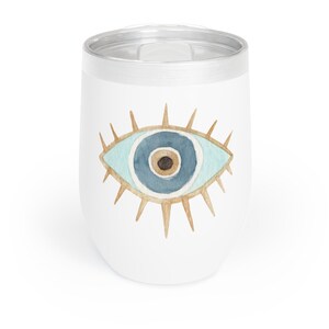 May include: White insulated wine tumbler with a silver rim and lid. The tumbler features a watercolor design of a blue eye with gold accents. The eye design is centered on the tumbler.