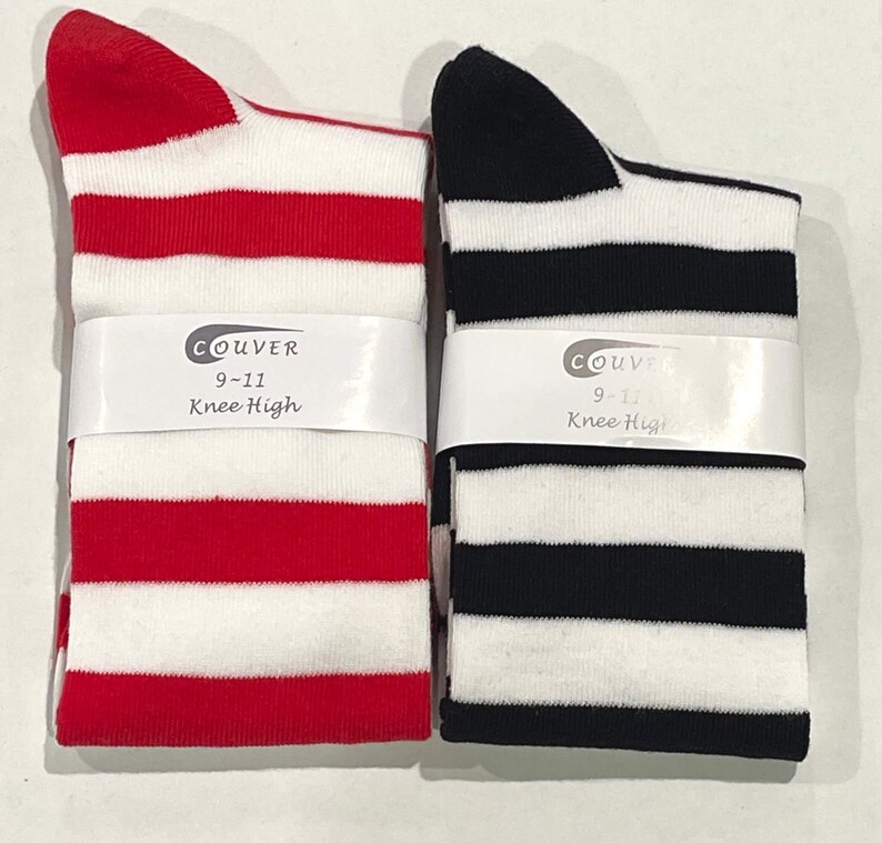 May include: Two pairs of knee-high socks with white stripes. One pair is red and white, the other is black and white. Both pairs have a label that says "Couvre 9-11 Knee High".