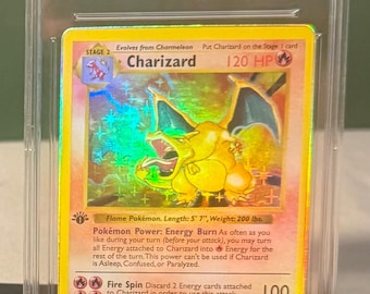 May include: A 1999 Pokemon Game Charizard Holo trading card graded GEM MT 10 by IPSA. The card features a yellow border, a holographic illustration of the orange dragon-like creature, 120 HP, and text detailing the Energy Burn power and Fire Spin attack.