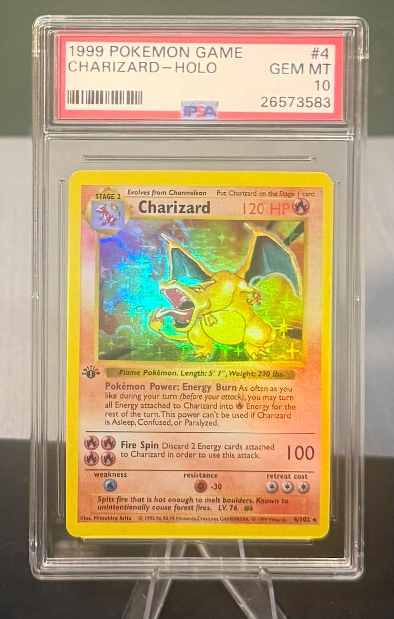May include: A graded 1999 Pok&eacute;mon Game Charizard-Holo card. The card features a holographic image of Charizard, a flame Pok&eacute;mon, with a length of 5' 7" and a weight of 200 lbs. The card is encased in a protective case.