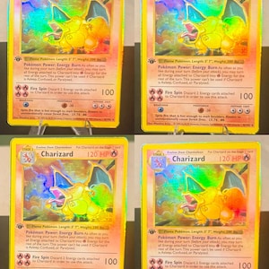 May include: A collection of four identical Charizard trading cards, each featuring a holographic illustration of the orange dragon-like creature. The cards display 120 HP, the Energy Burn power, and the Fire Spin attack with 100 damage points.