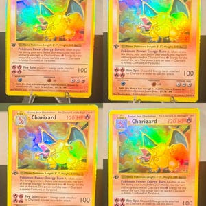 May include: A collection of four identical Charizard trading cards, each featuring a holographic illustration of the orange dragon-like creature. The cards display 120 HP, the Energy Burn power, and the Fire Spin attack with 100 damage points.