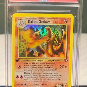 Puede incluir: Una carta de Pokémon 2000 Gym Challenge Blaine's Charizard Holo 1st Edition calificada. La carta presenta una imagen holográfica de Charizard. La carta está calificada GEM MT 10 por PSA. La carta mide 170 cm de largo y pesa 90,7 kg.