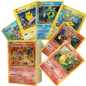 Może przedstawiać: Kolekcja holograficznych kart kolekcjonerskich przedstawiających różne postacie, w tym Pikachu Surf, Gyarados, Pikachu Vuelo, Magikarp, Charmeleon, Charmander oraz kartę Charizard umieszczoną na grubym stosie kart z żółtymi obwódkami.