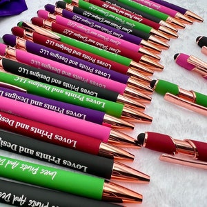 Pu&ograve; includere: Una collezione di penne con dettagli in oro rosa e una variet&agrave; di colori, tra cui verde, viola, rosa e nero. Ogni penna &egrave; incisa con il testo "Loves Prints and Designs LLC".