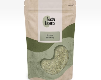 Può includere: Una busta verticale con un motivo astratto beige e verde contenente erbe essiccate. L'etichetta riporta il testo "busy beans" e "Organic Rosemary" sopra una finestra trasparente a forma di fagiolo che rivela il rosmarino verde all'interno.