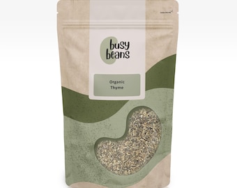 Pode incluir: Uma bolsa vertical com um padrão ondulado bege e verde contendo ervas secas. O rótulo apresenta o texto busy beans e Organic Thyme. Uma janela transparente em forma de feijão revela as folhas de tomilho secas no interior.