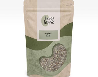 Può includere: Una busta verticale con un motivo astratto beige e verde contenente basilico biologico essiccato. L'etichetta riporta il testo "busy beans" e "Organic Basil" con una finestra trasparente a forma di fagiolo che rivela le erbe essiccate.