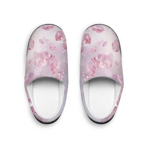 Peut inclure: Une paire de pantoufles d'intérieur avec un motif répété de pierres précieuses roses sur un fond rose clair et blanc. Les pantoufles ont un intérieur blanc et une bordure noire.