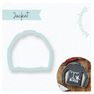 May include: A light blue jacket-shaped cookie cutter. Next to it is a finished cookie shaped like a black jacket with long sleeves, featuring white text that reads T BIRDS and a small white graphic of a bird in the center of the chest area.
