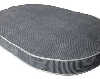 May include: A gray oval-shaped dog bed with a white piping around the edge. The bed is made of a soft, corduroy-like fabric.