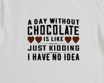 May include: White t-shirt with a black graphic that reads "A day without chocolate is like... Just kidding, I have no idea." with three chocolate hearts.