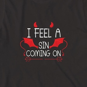 May include: Black t-shirt with a white graphic that says "I feel a sin coming on" with red devil horns and wings.