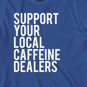 May include: Royal blue t-shirt with white text that reads "Support Your Local Caffeine Dealers".