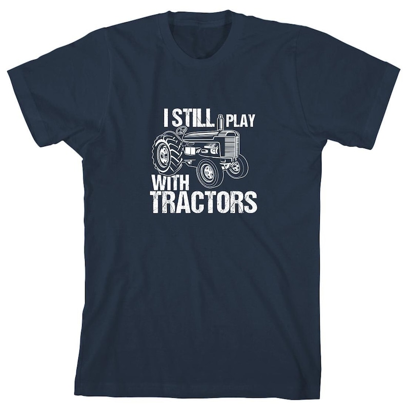 May include: A navy blue t-shirt with a white graphic of a tractor and the text "I Still Play With Tractors".