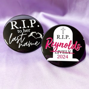 May include: Two black button pins with white text and a pink design. The first pin says "R.I.P. to her last name" with a skeleton hand heart design. The second pin says "R.I.P. Reynolds LIVELY 2024" with a tombstone design.