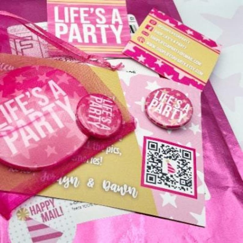 May include: A collection of pink and white party-themed stationery items. The items include buttons, cards, and stickers with the text "LIFE'S A PARTY" and star patterns. A QR code is also visible.