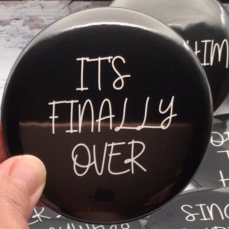 May include: Black button with the white text "IT'S FINALLY OVER". The button is round and glossy. Other buttons with text are visible in the background.