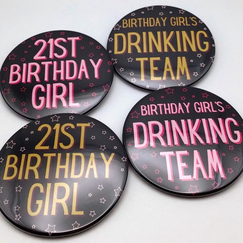 Four round black pinback buttons featuring pink and gold lettering that read “21st Birthday Girl” and “Birthday Girl’s Drinking Team,” arranged together on a white background.