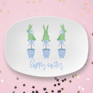 May include: White oval serving platter with three green bunny topiaries in blue pots and a blue "Happy Easter" message.