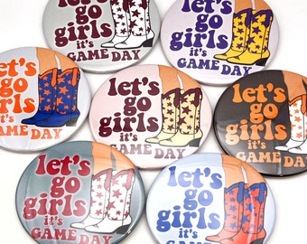 May include: Seven round, colorful buttons with the text "Let's go girls it's game day" and a pair of boots with stars on them.