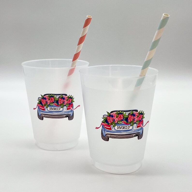 May include: Two frosted plastic cups with a car graphic on the front, decorated with flowers and the word "DIVORCED". Each cup has a striped paper straw. One straw is red and white, the other is green and white.