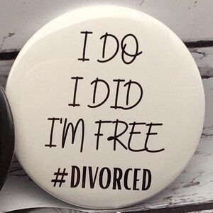 May include: A white button with black text that reads "I DO I DID I'M FREE #DIVORCED". The button is round and has a glossy finish. The text is in a handwritten style font.