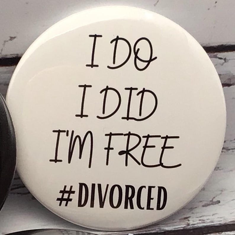 May include: A white button with black text that reads "I DO I DID I'M FREE #DIVORCED". The button is round and has a glossy finish. The text is in a handwritten style font.