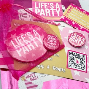 May include: Pink and white 'Life's a Party' themed party supplies in a pink organza bag. The supplies include a large round sticker, a small button, a business card, and a card with a QR code.