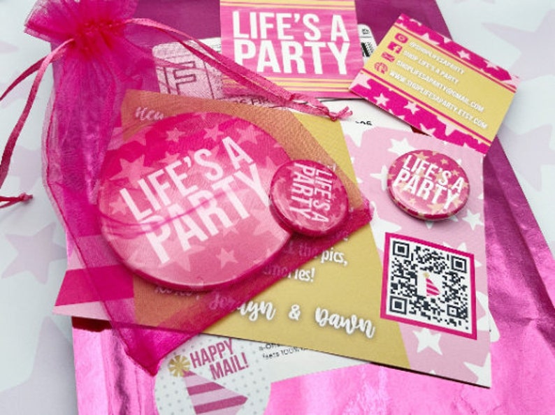 May include: Pink and white 'Life's a Party' themed party supplies in a pink organza bag. The supplies include a large round sticker, a small button, a business card, and a card with a QR code.