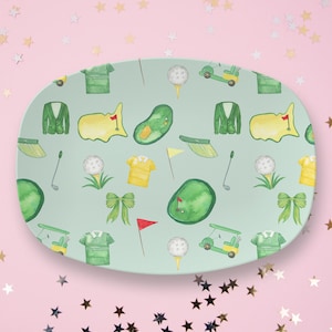 May include: A light blue oval serving platter with a repeating pattern of golf-themed illustrations. The illustrations include golf clubs, golf balls, golf carts, golf courses, and golf apparel.