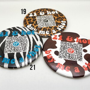 Puede incluir: Tres botones redondos con diferentes dise&ntilde;os de estampado animal. Cada bot&oacute;n tiene un c&oacute;digo QR y el texto "21 & hot buy me a shot".