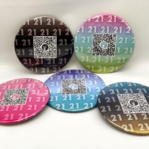 May include: Five round, colorful buttons with a gradient design. Each button features a black and white QR code with the number "21" repeated around the edge.