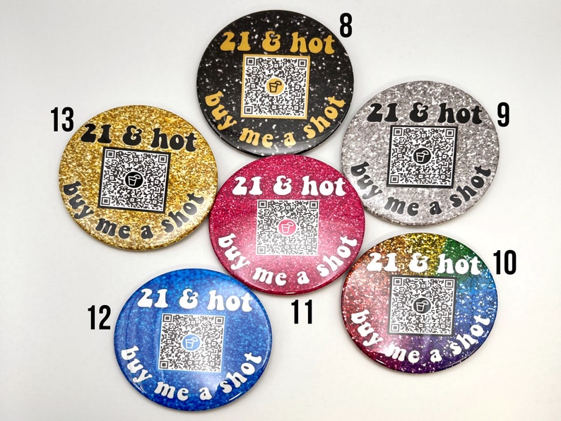 Puede incluir: Seis botones redondos con fondos de purpurina y el texto "21 & hot buy me a shot" en letras blancas. Cada bot&oacute;n tiene un c&oacute;digo QR &uacute;nico y un n&uacute;mero del 8 al 13.