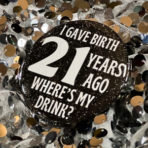 May include: Black and white button with glitter. The button says "I gave birth 21 years ago where's my drink?"