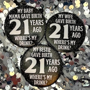 May include: Three black and white round buttons with glitter. Each button has the text "21 years ago" and "Where's my drink?" with a different phrase above the number. The phrases are "My baby mama gave birth", "My wife gave birth", and "My bestie gave birth".