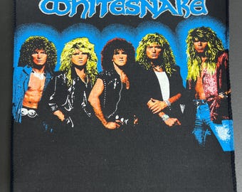 Puede incluir: Un parche bordado negro y azul con el nombre de la banda "Whitesnake" en letras blancas. Cinco hombres aparecen en el parche, vistiendo chaquetas de cuero negras y jeans. Los miembros de la banda están de pie frente a un fondo azul.