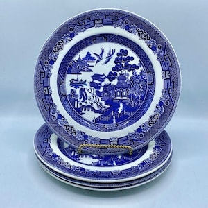 May include: Three blue and white willow pattern dinner plates stacked on top of each other.