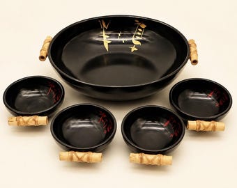 May include: A large black serving bowl and four smaller matching bowls, each featuring a glossy finish, gold-toned calligraphy accents, and decorative light-colored bamboo-style handles wrapped with thin cord at the sides.