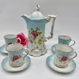 May include: A vintage tea set with a blue and white floral design. The set includes a teapot, four cups, and four saucers.