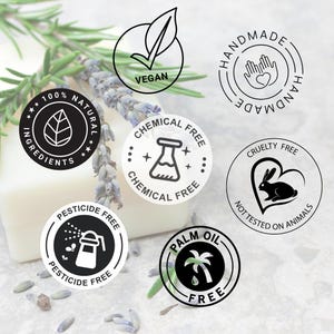 May include: A white bar of soap with black and white labels. The labels state "100% Natural Ingredients", "Vegan", "Chemical Free", "Pesticide Free", "Palm Oil Free", "Cruelty Free - Not Tested on Animals", and "Handmade".